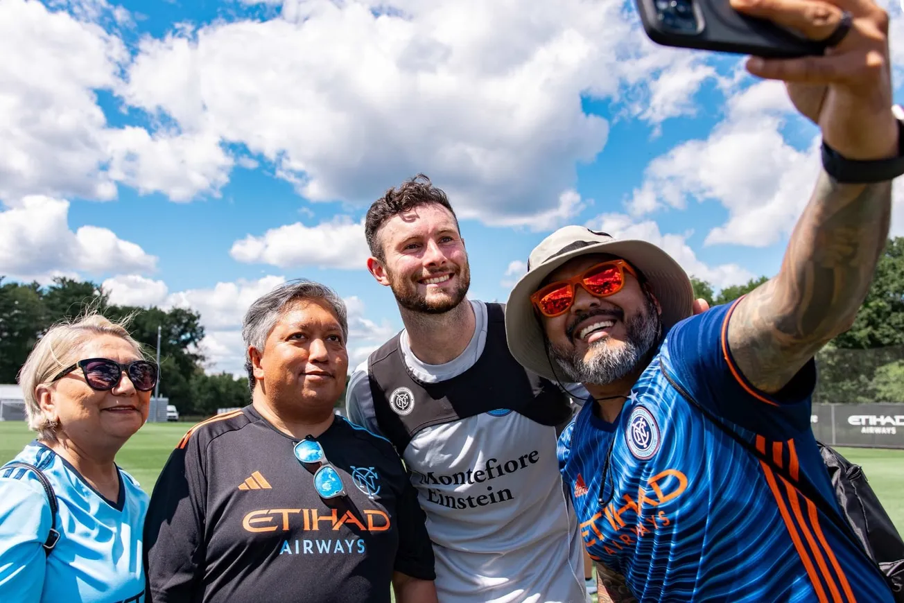 New York City FC midfielder Aiden O'Neill stops for a selfie with three NYCFC fans after training